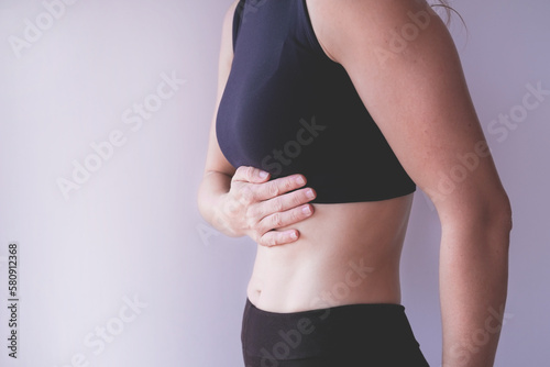 Woman suffering from stomach abdominal ache and holding hand on the belly, isolated on white background, studio shot