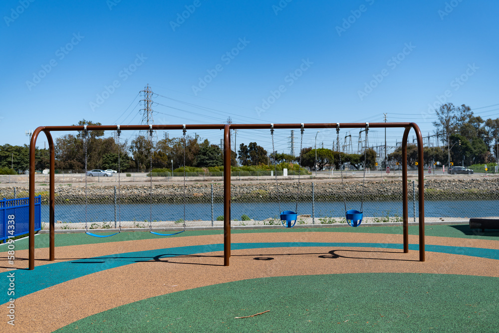 Metal four seat swings outdoors. Childrens swings on playground. Swings seats suspended by chains