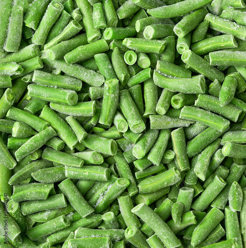 Frozen cut green beans close up top view background.