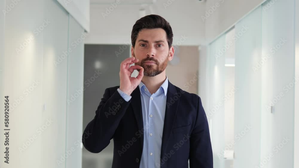 Young man in professional attire, making the silence gesture with finger on his lips. Businessman office worker, possibly handling sensitive information, conveys professionalism and confidentiality. Young man in professional attire, making the silence gesture with finger on his lips. Businessman office worker, possibly handling sensitive information, conveys professionalism and confidentiality.