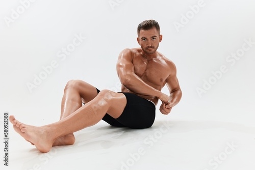 Man athletic body bodybuilder in briefs with naked torso abs full-length in the background, fitness classes. Advertising, sports, active lifestyle, competition, challenge concept. © SHOTPRIME STUDIO