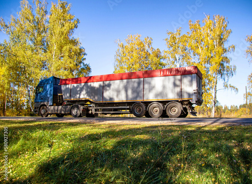 Transportation in special trailers of bulk cargoes of sand and coal on country roads. Automobile cargo transportation, industry. Copy space for text photo