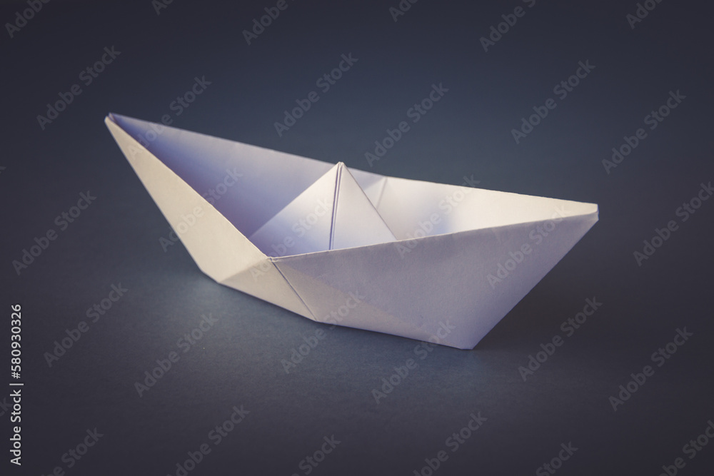 White paper boat origami isolated on a grey background White paper boat origami isolated on a grey background