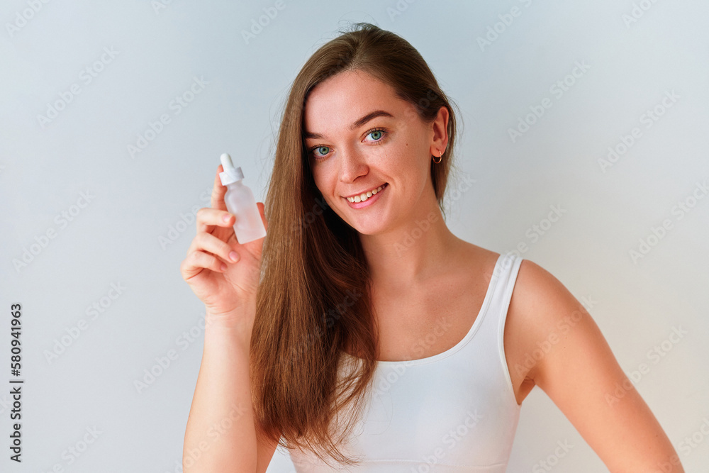 Portrait of attractive young woman holding face serum bottle for beautiful healthy skin Portrait of attractive young woman holding face serum bottle for beautiful healthy skin