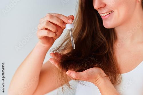 Woman using serum for beautiful healthy hair