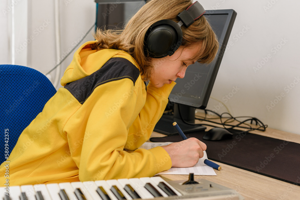 Teen boy piano player writing song in music book Teen boy piano player writing song in music book