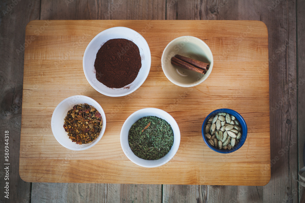 High angle view of various spices in bowls on cutting board over wooden table High angle view of various spices in bowls on cutting board over wooden table