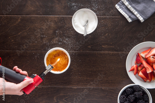 Cropped image of hand using butane torch while making creme brulee at table photo