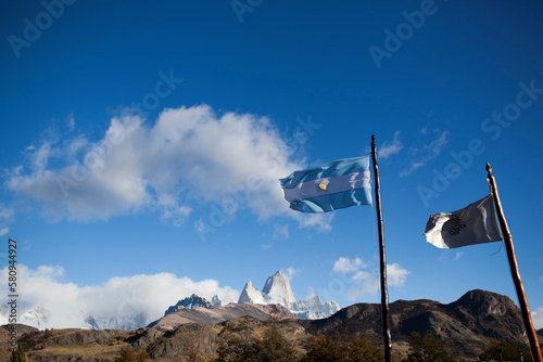 Low angle view of flags by mountain against blue sky photo