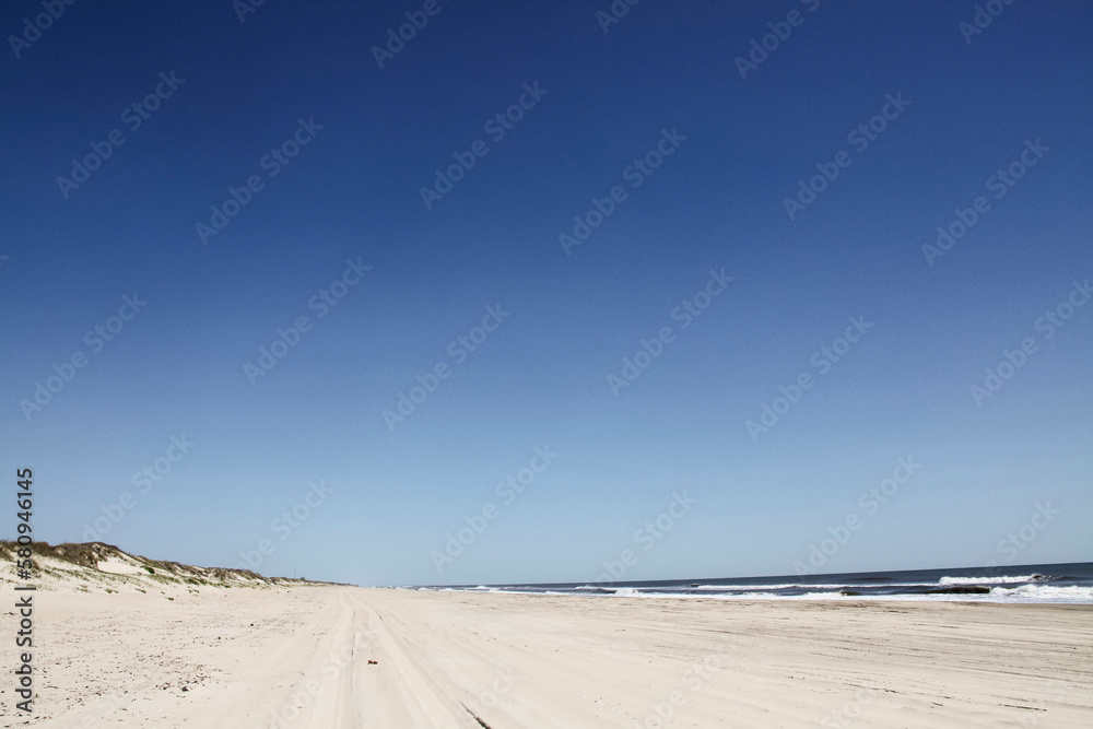 Scenic view of beach against clear blue sky during sunny day Scenic view of beach against clear blue sky during sunny day