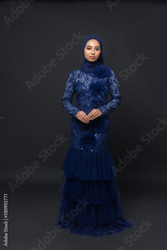 A teenager model use blue dress. She's pose in the studio indoor. She's pose in dark gray background with elegant pose. She's look like beautiful and graceful
 photo