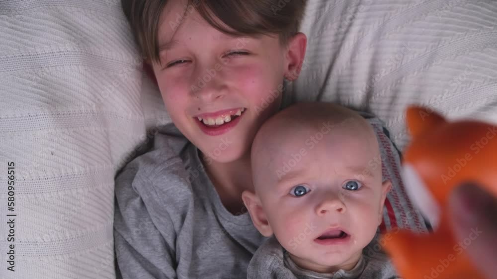 two brothers , small and large, older and younger lie playing and having fun together on a light background top view two brothers , small and large, older and younger lie playing and having fun together on a light background top view