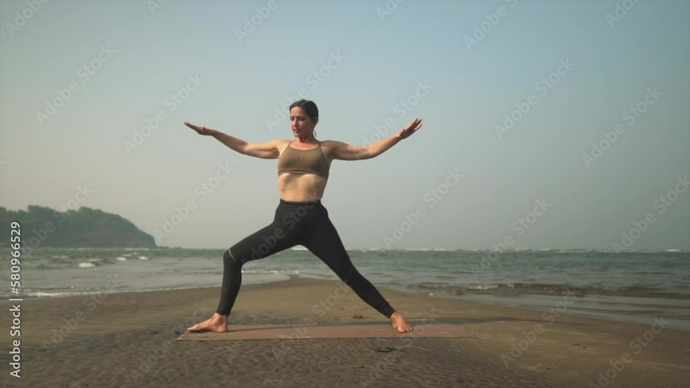 Warrior 2 yoga pose being completed in slow mo by teacher on coastline. Warrior 2 yoga pose being completed in slow mo by teacher on coastline.