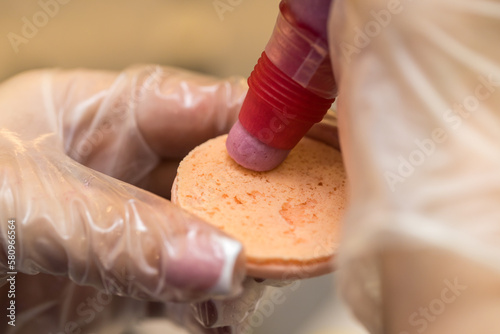 the pastry chef squeezes the filling onto macarons cookies. close-up. home bakery concept.