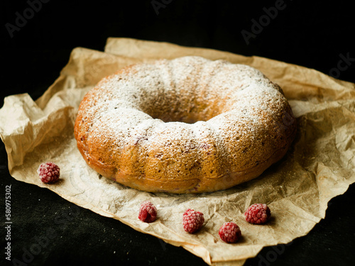Vanilla bundt cake with fresh raspberries on a black table. vegetarian, lean, dairy and egg free. Selective focus. Close up