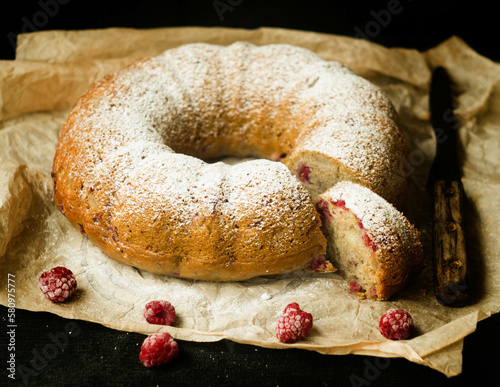 Vanilla bundt cake with fresh raspberries on a black table. vegetarian, lean, dairy and egg free. Selective focus. Close up