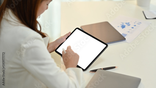Side view of young woman office worker using stylus pen writing on blank digital tablet screen © Prathankarnpap
