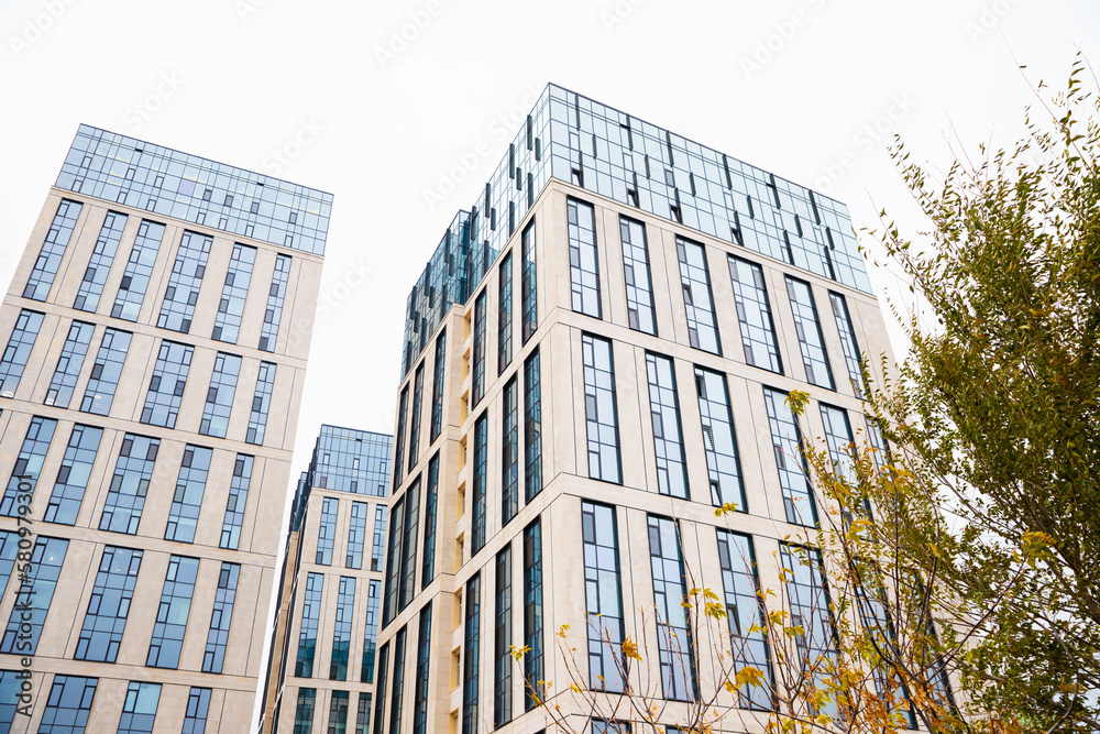 Blue beige modern apartment building, tree. Tile and glass facade. View