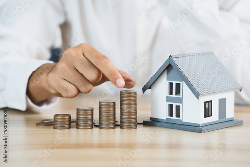 House model and coin holder money on the table for finance and banking concepts. Property investment mortgage and home rental concept earning from home