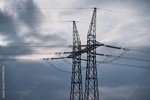 Pylons of a high-voltage power line in front of a cloudy sky