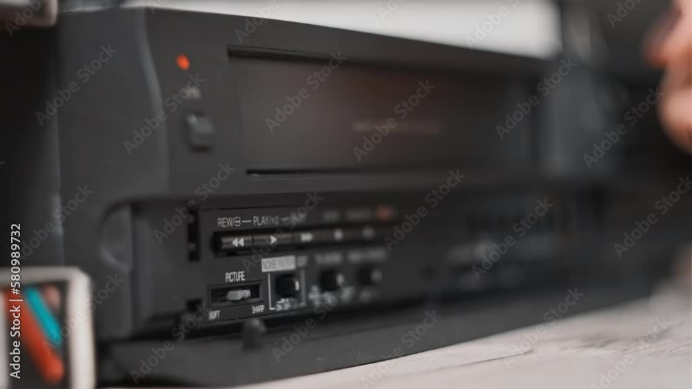 Eject VHS tape cassette from VCR player. Female hand pulls out VHS from