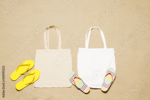 Mockup shopper handbag beach sand background. Top view copy space shopping eco reusable bag. Flip flops accessories. Template blank top view white cotton material canvas cloth. Empty mock-up beach