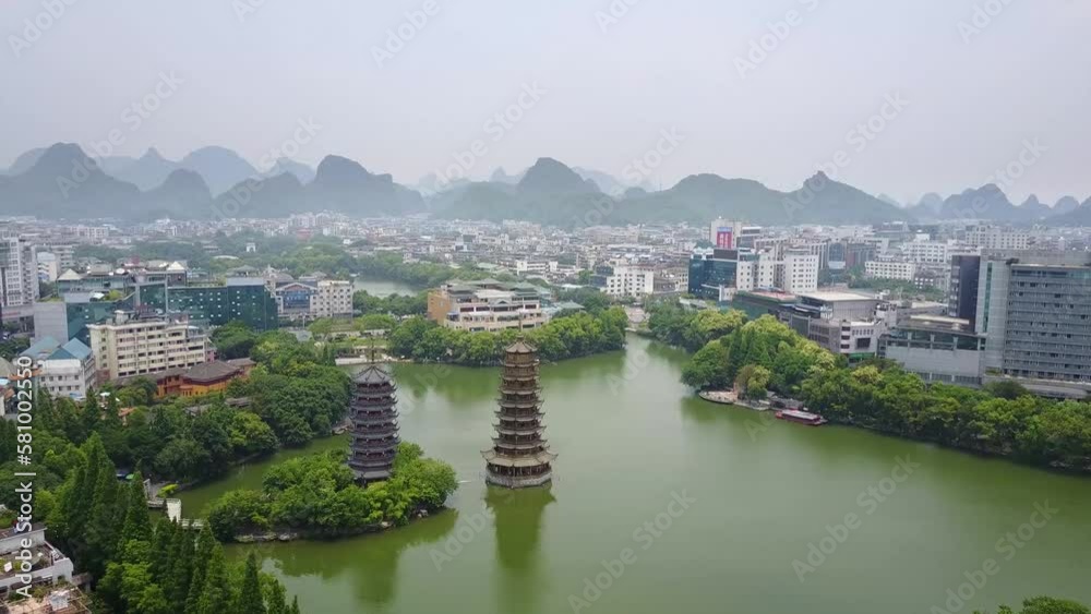 Aerial Shot of the Guilin Sun and Moon Pagodas at Lake Shanhu with the City and Jagged Peak in the Background, Guangxi, China (UHD)