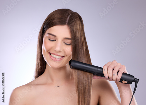 Hair straightener, face and beauty smile of woman in studio isolated on a gray background. Haircare, happy and young female model with flat iron product for salon treatment, balayage or hairstyle.