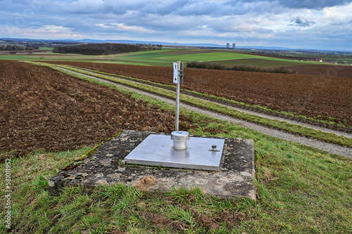 Verzinkte quadratische Schachtabdeckung mit Dunsthut mit Betonrahmen auf einem Feld photo