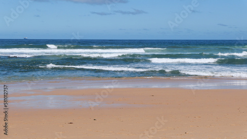 Beautiful beach scene with sand in foreground and rolling waves in background