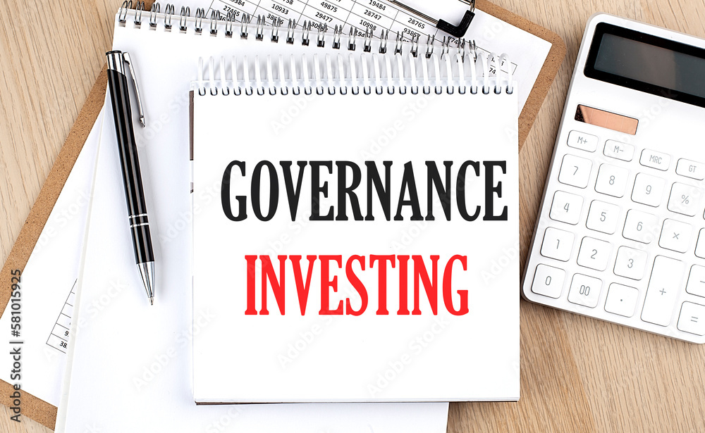 GOVERNANCE INVESTING is written in white notepad near a calculator, clipboard and pen. Business concept GOVERNANCE INVESTING is written in white notepad near a calculator, clipboard and pen. Business concept