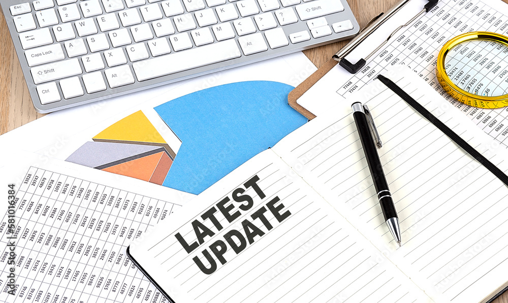 LATEST UPDATE text on notebook with chart and keyboard LATEST UPDATE text on notebook with chart and keyboard