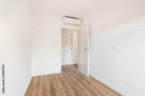 View of the front door to a small white air-conditioned room with wooden floor in a hotel. Concept of simple renovation or an empty apartment after move