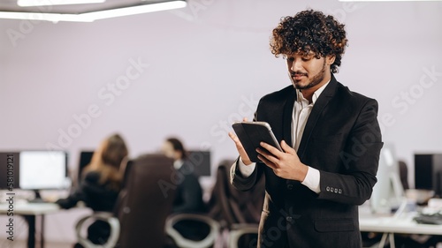 Handsome businessman using tablet. Indoor shot of focused office manager with digital device