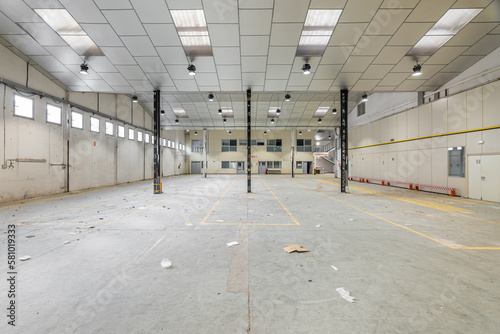 Fototapeta Empty spacious hall with metal beams and lamps prepared for a parking lot or factory