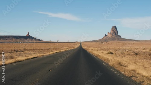 Driving on highway in hot dry desert area with amazing red rock formations Monument Valley park in Arizona United States. Pov from moving vehicle car riding downhill on asphalt road going to horizon