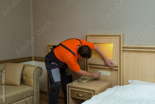 Obraz na plátně Male worker repairing electric socket hotel room.