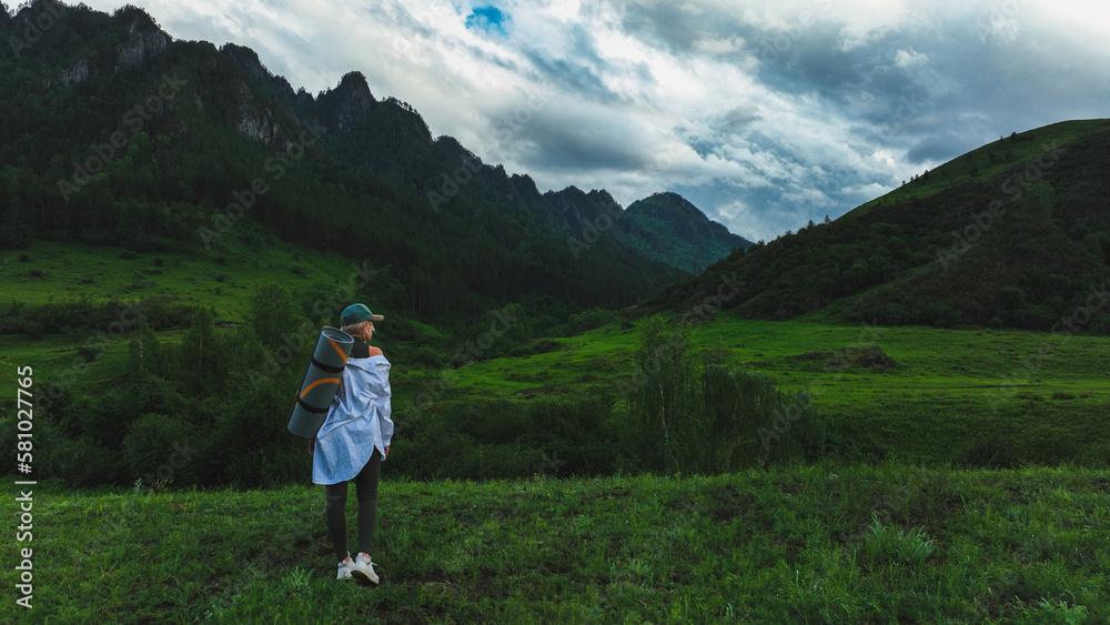 The girl admires the beautiful view of the mountains in summer time. Travel concept