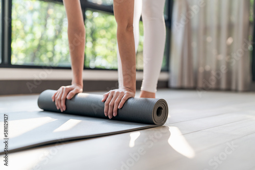 Fitness woman folding exercise mat before working out in yoga studio. rolling Yoga mat  after training healthy lifestyle.