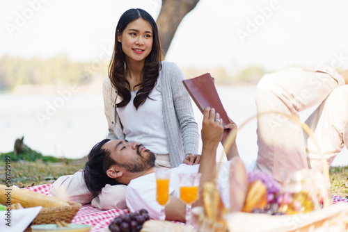 Happy romantic asian couple lying down at the park  picnic time in summer holidays vacation.