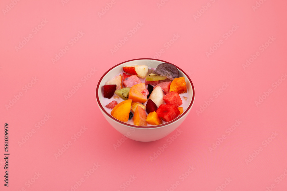 Bowl of Es Campur or Sop Buah on pink background, selective focus, copy space. Design element. Fruit salad with yogurt. Fruit iced soup. Popular indonesian fruits cocktail dessert Bowl of Es Campur or Sop Buah on pink background, selective focus, copy space. Design element. Fruit salad with yogurt. Fruit iced soup. Popular indonesian fruits cocktail dessert