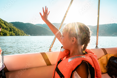 Little girl on a boat waving out at the sea photo