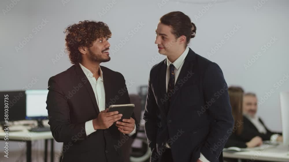 A video in which an employee of a financial company shows something to his colleague on a digital tablet. Two men in business suits are watching something on a digital tablet during a break. A video in which an employee of a financial company shows something to his colleague on a digital tablet. Two men in business suits are watching something on a digital tablet during a break.