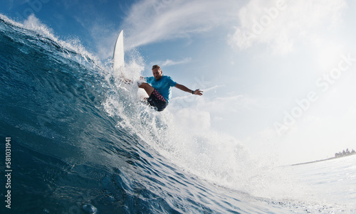 Pro surfer rides the wave. Young man surfs the ocean wave in the Maldives and aggressively turns on the lip. Splitted above and underwater view