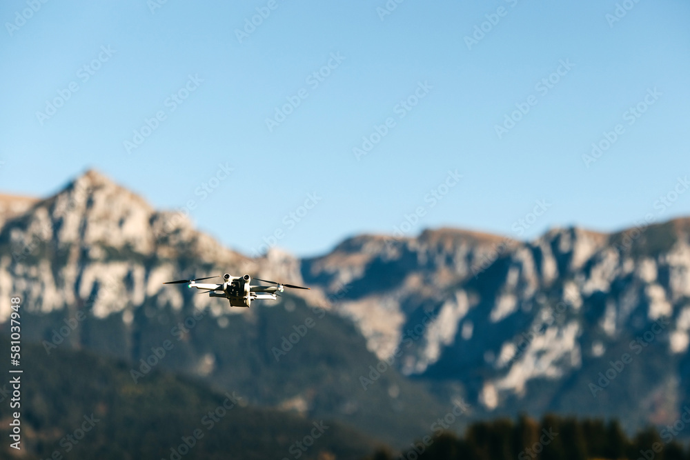Drone flying over mountains on blue sky background.