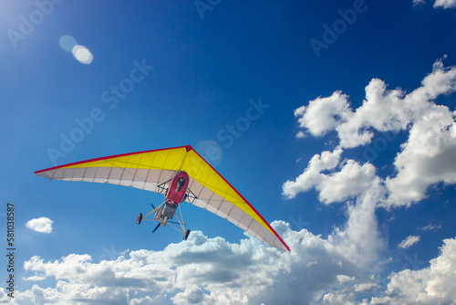 Motorized steerable paraglider flies in the sky, view from below.