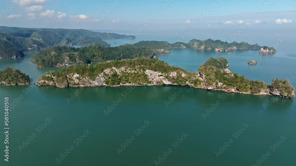 Breathtaking drone shot showing rocky islands in ocean covered with plants during sunny day - Tourist boats arriving during trip - 