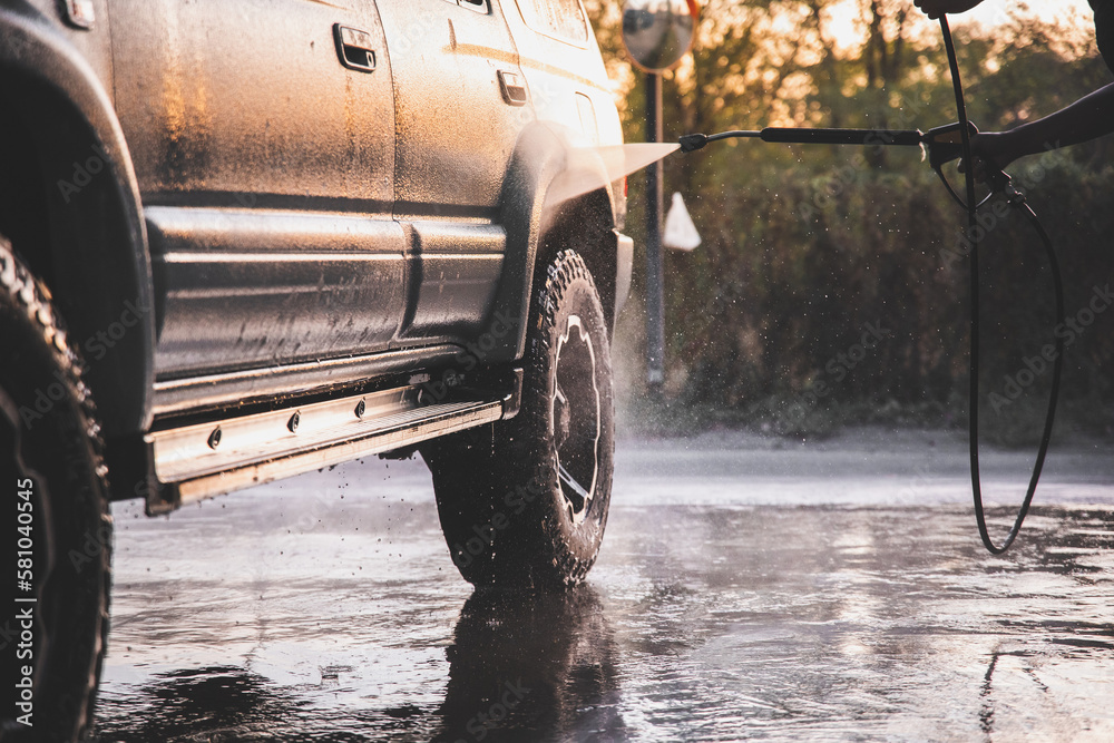 Washing SUV car at a self-service car wash with a high-pressure water jet after off-road driving. Washing SUV car at a self-service car wash with a high-pressure water jet after off-road driving.