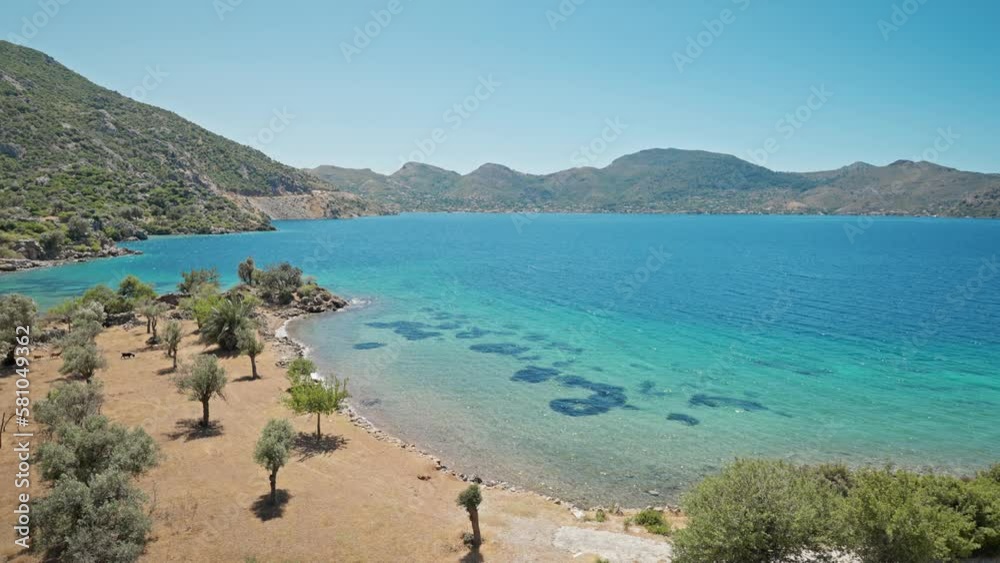 attractive slim tanned woman traveler in orange sundress stands on shore of beautiful bay with turquoise water and paradise empty sea beach. Girl walks at sea coast in Turkey, Marmaris region attractive slim tanned woman traveler in orange sundress stands on shore of beautiful bay with turquoise water and paradise empty sea beach. Girl walks at sea coast in Turkey, Marmaris region