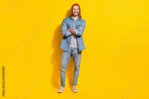Photo of handsome friendly nice guy with long hairstyle dressed jeans shirt standing arms folded isolated on yellow color background © deagreez